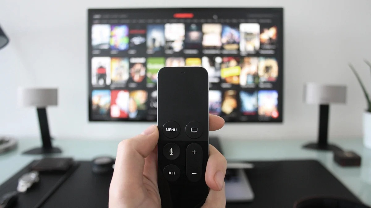 Persona usando un control remoto frente a una Smart TV con una plataforma de streaming abierta.